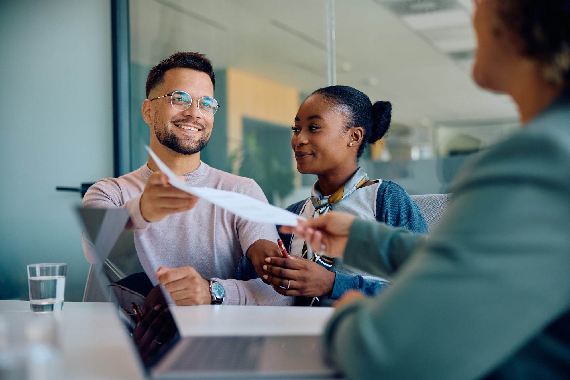 Young happy couple giving documents to their insurance agent during a meeting in the office.