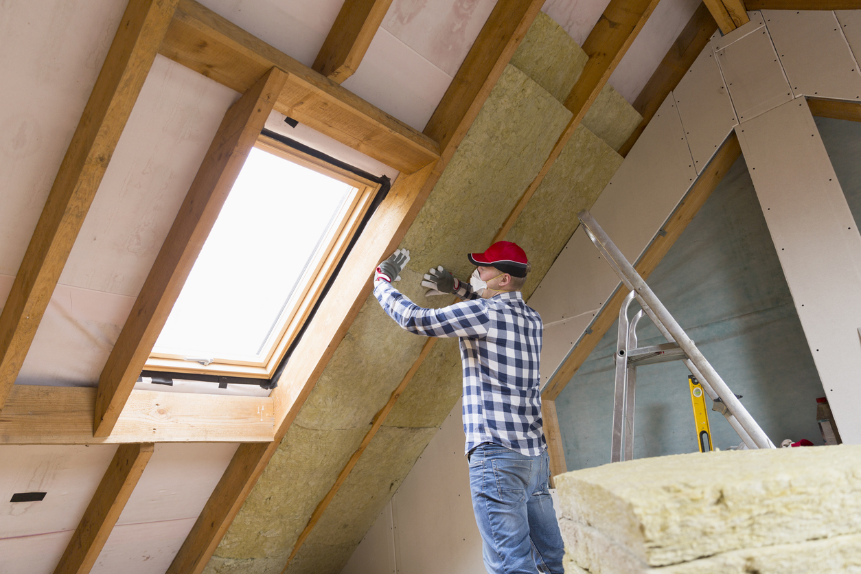 Man installing thermal roof insulation layer – using mineral wool panels. Attic renovation and insulation concept